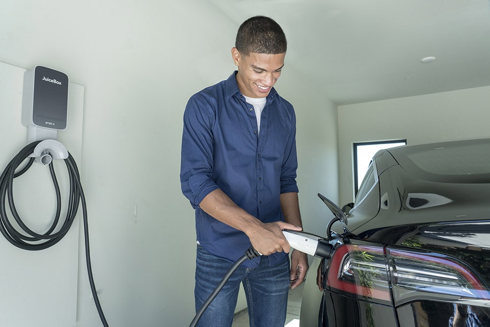 Image of man charging his electric vehicle using a residential Juicebox EV charger